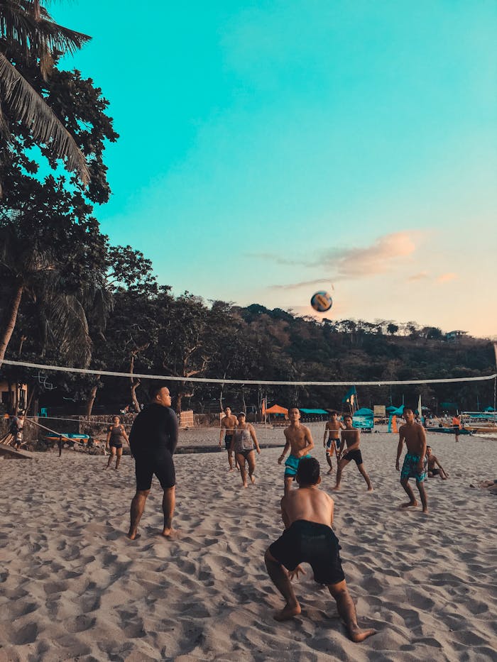 A vibrant scene of friends playing beach volleyball at sunset with scenic views.